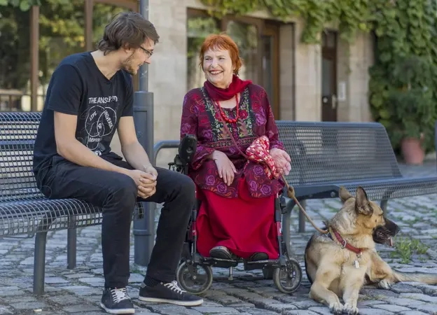 Eine Frau mit Hund und im Rollstuhl unterhält sich mit einem jungen Mann