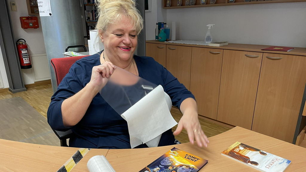 Eine Frau klebt eine durchsichtige Schutzfolie auf ein Buch.