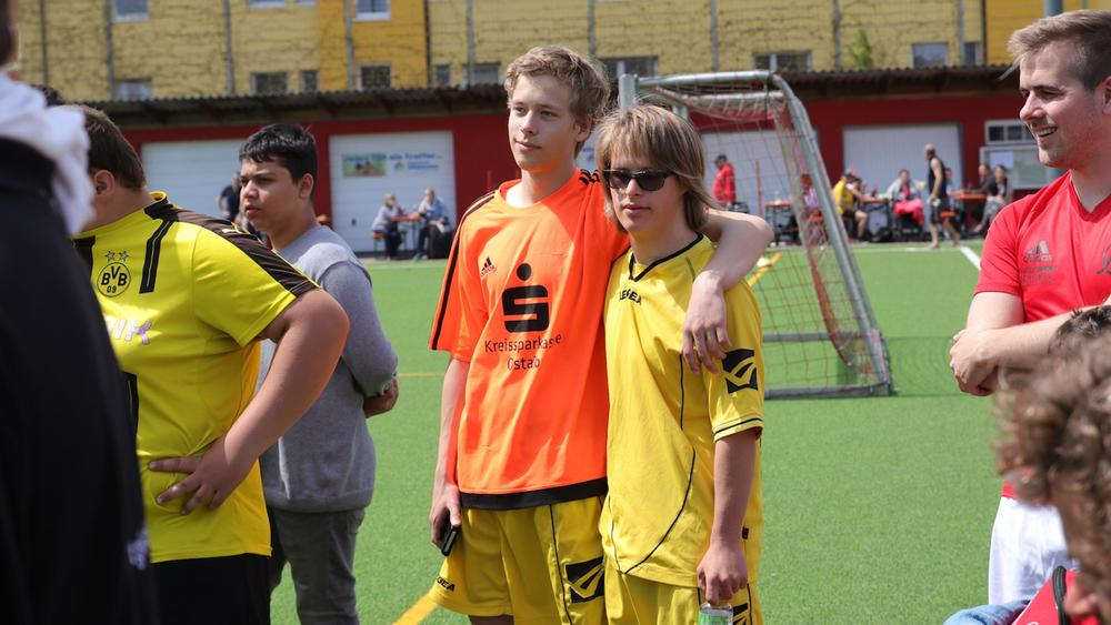 zwei jungs stehen auf dem spiefeld und umarmen sich