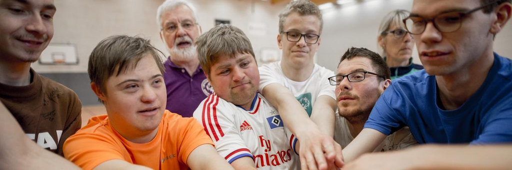 Ein Gruppe von Menschen mit und ohne Behinderung fassen sich gemeinsam an den Händen.