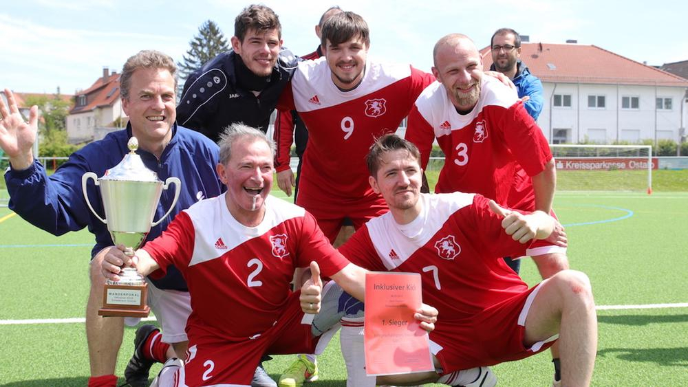eine fußballmannschaft, einer der mitspieler hält einen pokal in der hand