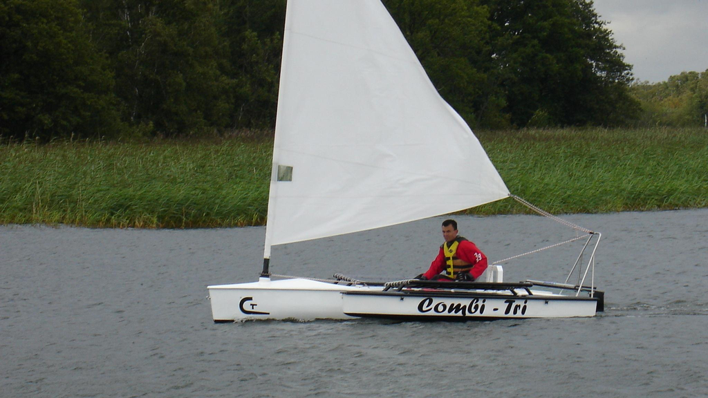 In einem kleinen Segelboot auf dem Wasser sitzt ein Mann.