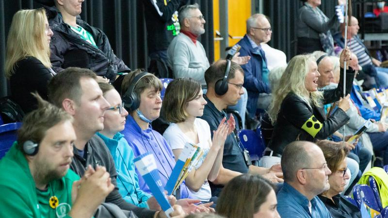 Fans, davon viele blind und mit Kopfhörer, während einer Sportveranstaltung in einer Halle