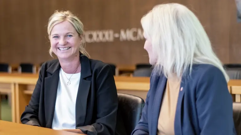 Zwei Frauen sitzen an einem Tisch und unterhalten sich.