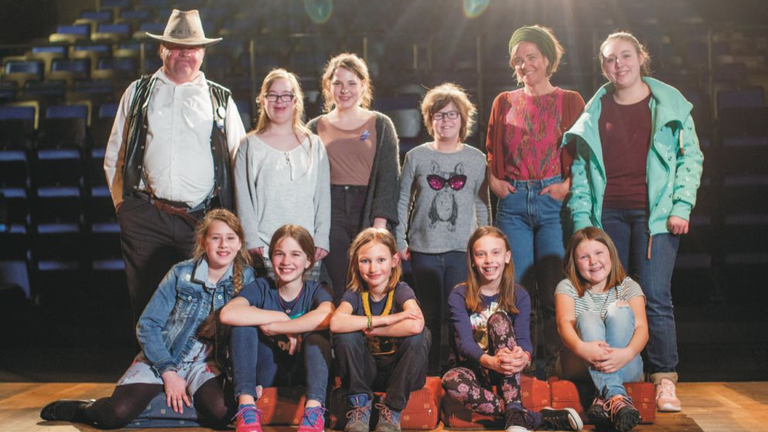 Gruppenfoto von elf Jugendlichen und Erwachsenen in leerem Theatersaal