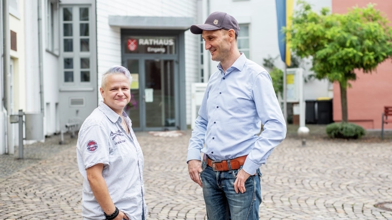 Zwei Personen stehen vor dem Rathaus in Nieder-Olm.