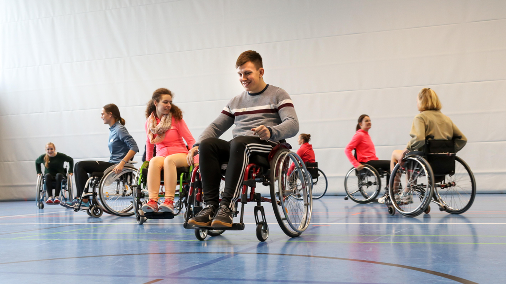 Eine Gruppe junger Menschen im Rollstuhl in einer Sporthalle.