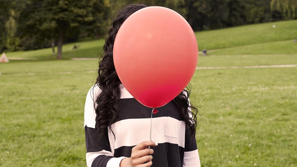 Mädchen mit Ballon vor dem Gesicht