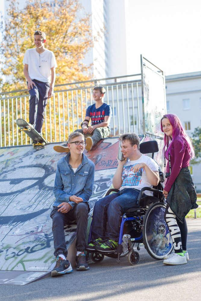Jugendliche mit und ohne Behinderung treffen sich an einer Skaterrampe. 