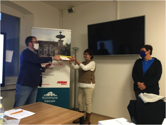 Erlangens Oberbürgermeister Florian Janik übergibt ein Tablet an das Kommune Inklusiv-Team.