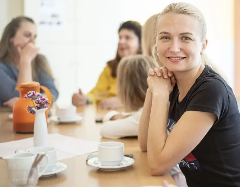 Mehrere Menschen sitzen an einem Tisch und trinken Kaffee,.