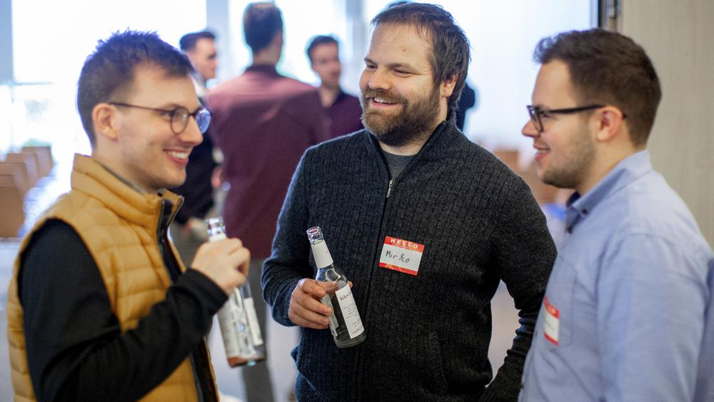 Drei Männer stehen zusammen und lachen.