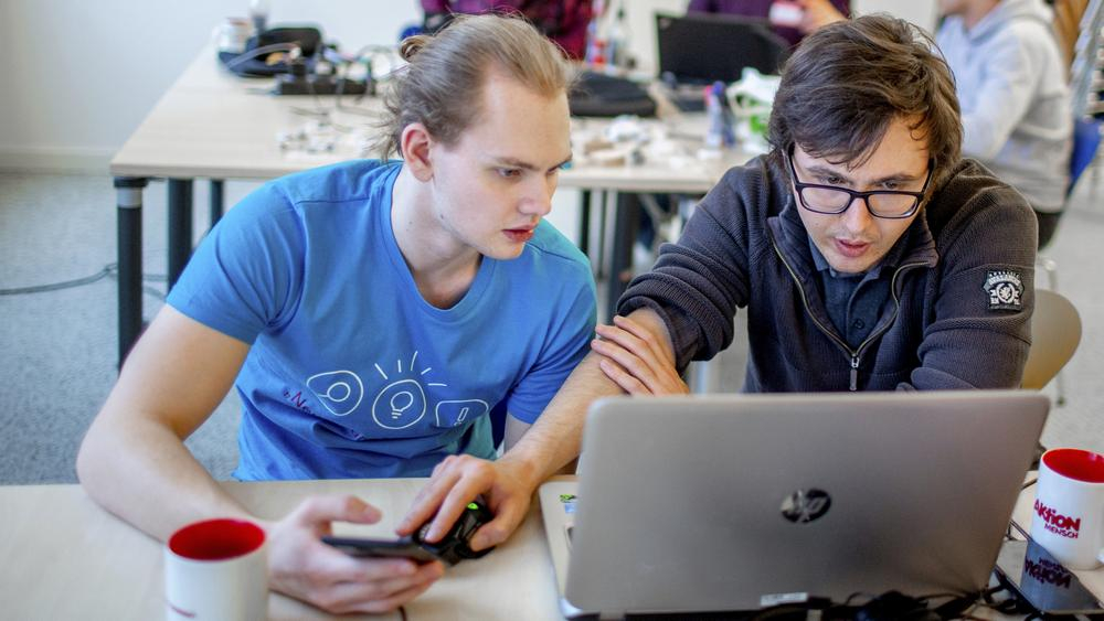 Zwei Männer blicken konzentriert auf einen Laptop.