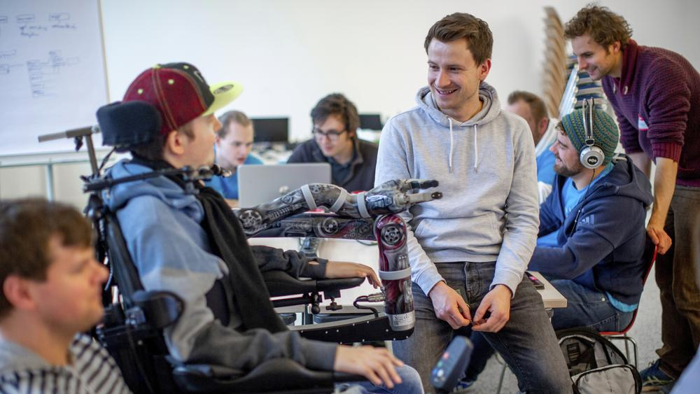 Zwei Männer, einer davon im Rollstuhl, unterhalten sich.