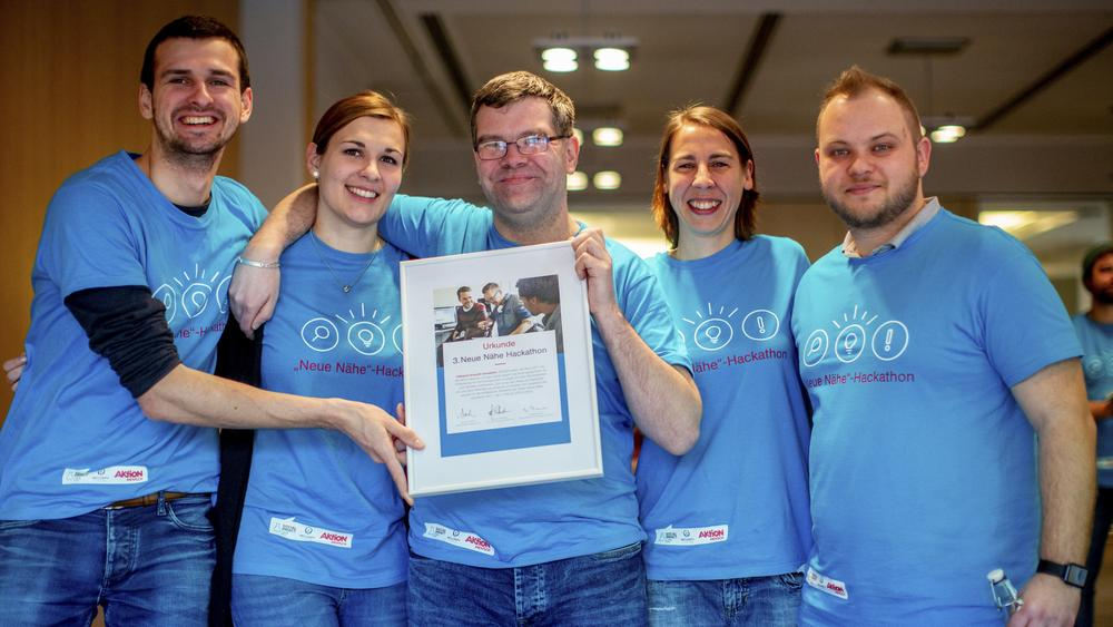 Eine Gruppe Menschen in blauen T-Shirts lächeln in die Kamera.