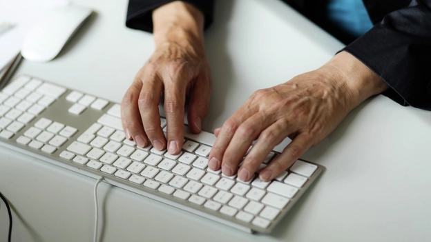 Zwei Hände liegen auf einer Computertastatur und tippen.