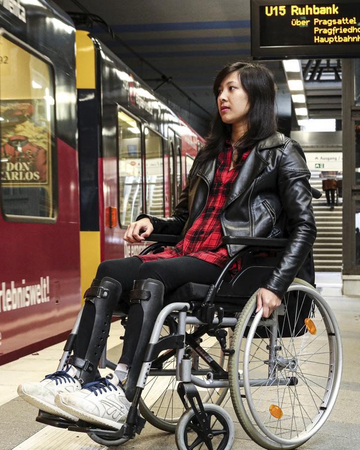 Eine junge, dunkelhaarige Frau steht mit ihrem Rollstuhl an einer U-Bahn-Haltestelle. Die Bahn ist gerade eingefahren.