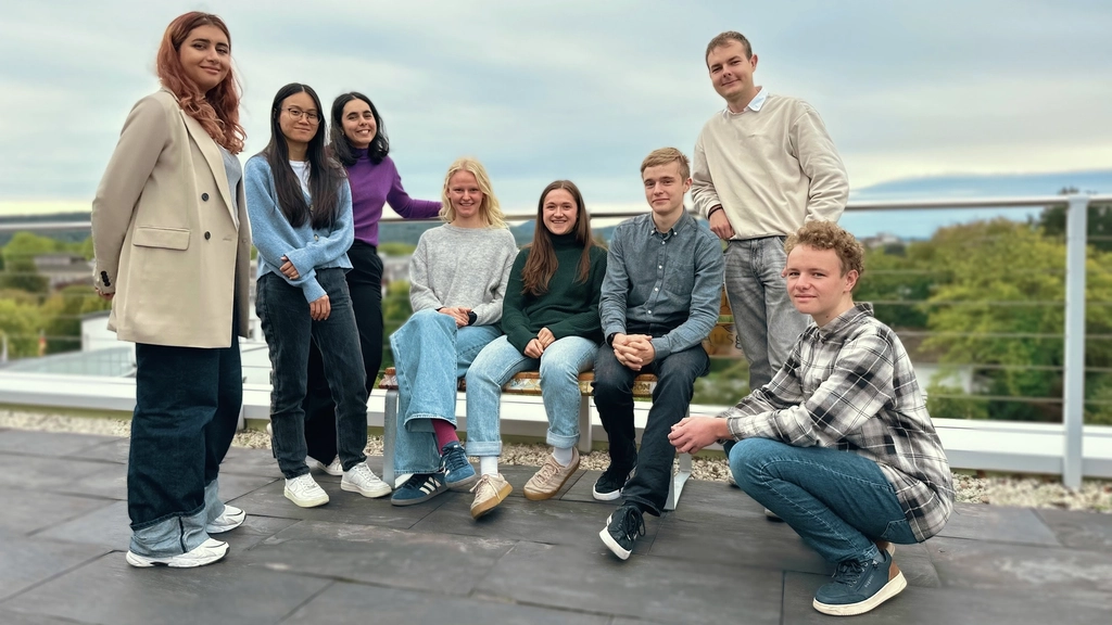 Gruppenbild mit acht jungen Menschen auf der Aktion Mensch-Dachterrasse. Im Hintergrund ist das Siebengebirge zu sehen.