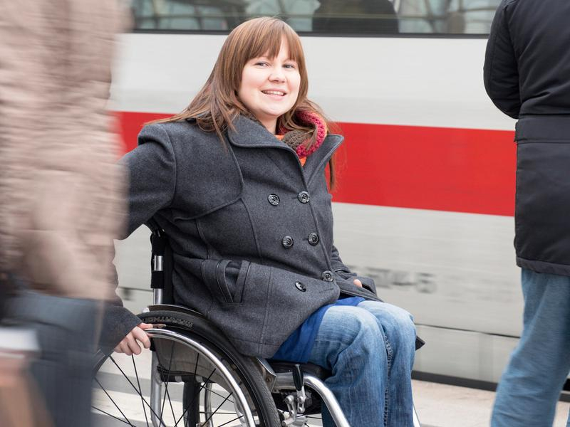 Eine Frau fährt im Rollstuhl auf einem Bahnhofsgleis