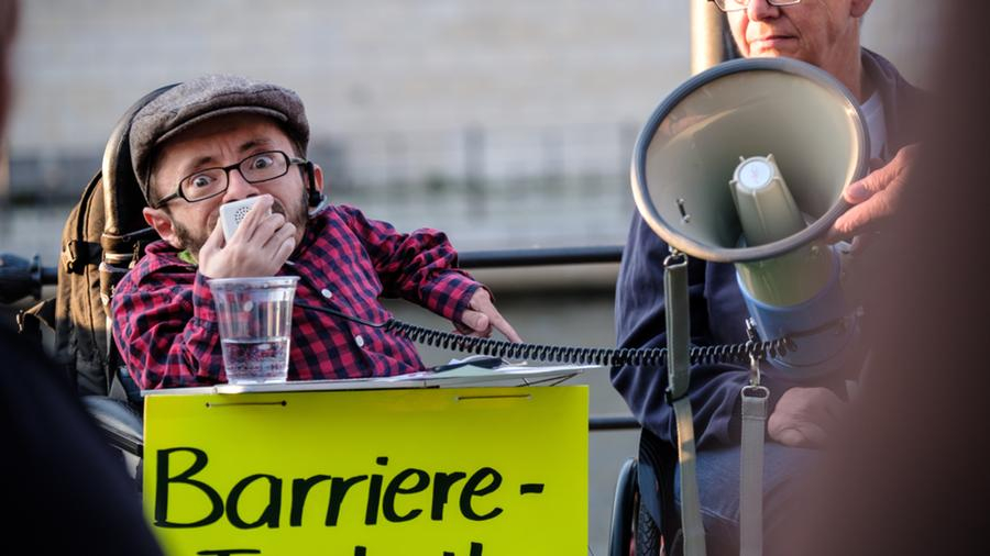 Ein Mann im Rollstuhl spricht durch den Lautsprecher