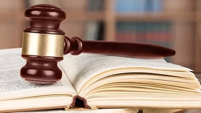 Ein Richterhammer liegt auf einem aufgeschlagenen Buch.