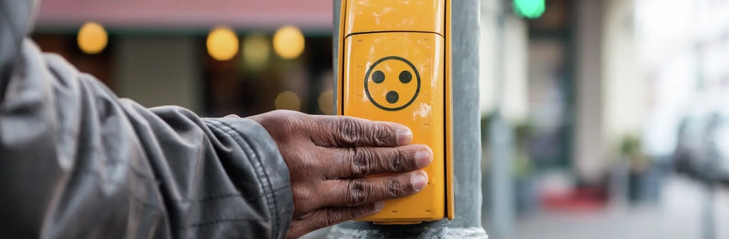 Eine Hand liegt auf einem Ampel-Anforderungstaster.