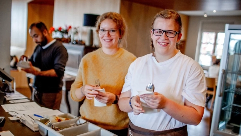 Zwei Frauen in einem Gastrobetrieb wickeln Besteck in Servietten