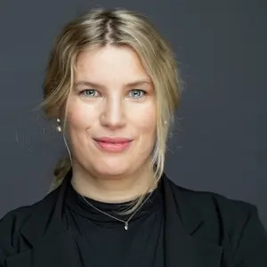 Porträt von Gesa Kobs. Sie trägt einen blonden Pferdeschwanz und einen schwarzen Blazer.