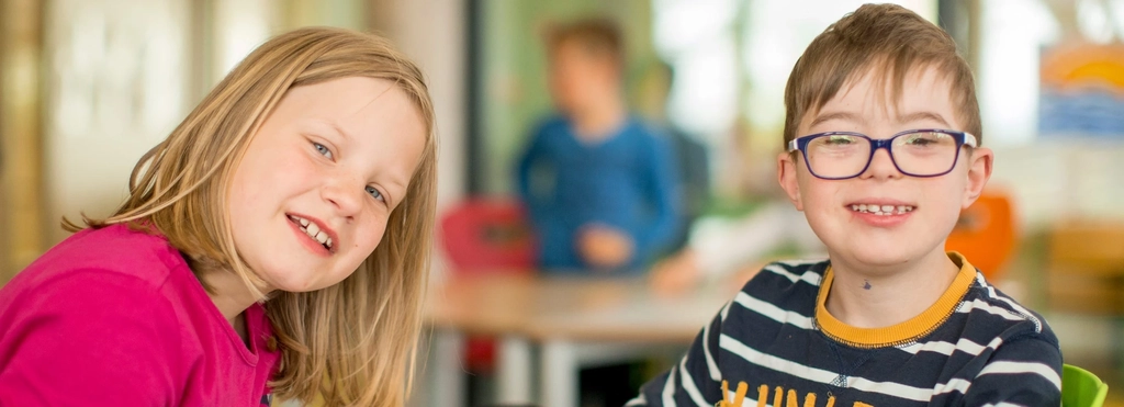 Zwei Kinder lächeln in die Kamera.