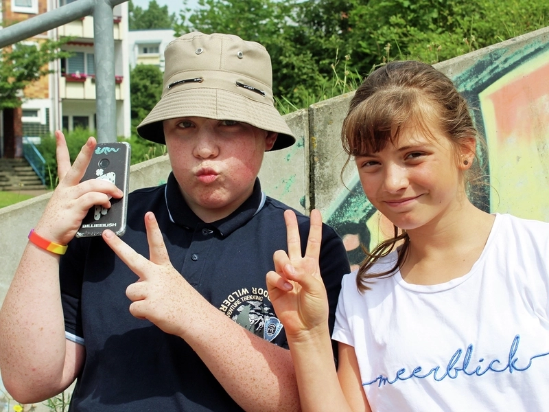Ein Junge und ein Mädchen posieren mit Handy