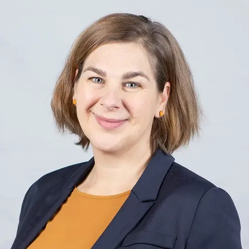 Porträt von Annegret Prigge: eine Frau mit kinnlangem Haar. Sie trägt einen Blazer und lächelt in die Kamera.