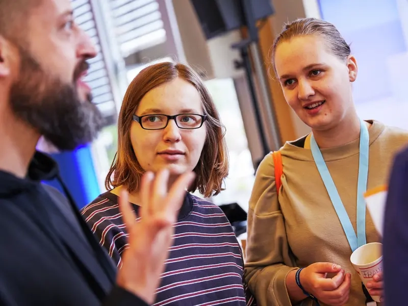 Vier junge Erwachsene stehen zusammen und unterhalten sich.