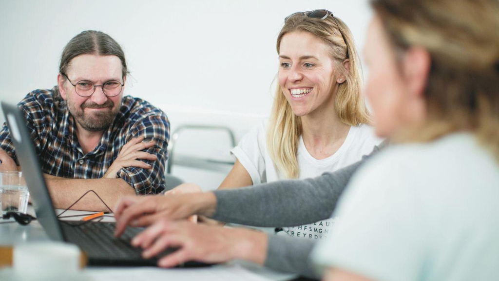 Eine Gruppe von Kolleg*innen arbeitet zusammen an einem Laptop