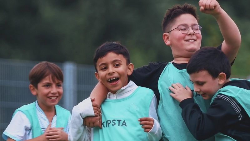 Vier Jungen in Trainingslaibchen umarmen sich und feiern zusammen einen Erfolg.