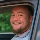 Gewinner David sitzt in seinem neuen Auto. Das Fenster an der Fahrerseite ist offen und er hält lächelnd zwei Glücks-Lose in die Kamera.