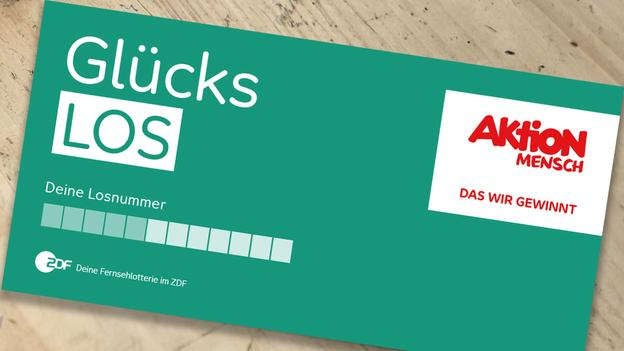 Ein Glücks-Los liegt auf einem Tisch. Daneben steht eine Tasse Kaffee.