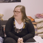 Lisa, eine junge Frau mit Downsyndrom, trägt eine Brille und lange dunkelblonde Haare.