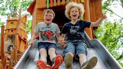 Zwei Jungs, einer davon mit Downsyndrom, auf einer Rutsche