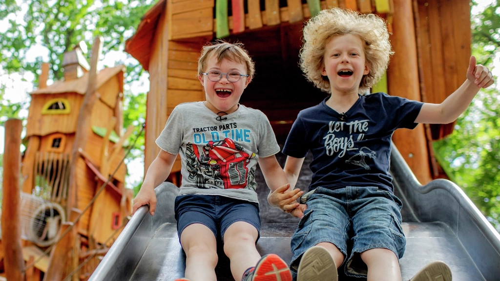 Zwei Jungs, einer davon mit Downsyndrom, auf einer Rutsche