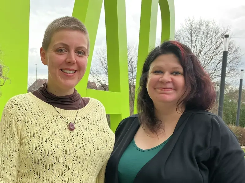 Drei Frauen stehen nebeneinander und schauen lächelnd in die Kamera.