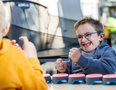 Ein Junge mit Brille und Zahnspange freut sich breit grinsend über einen Triumph im sportlichen Wettstreit.