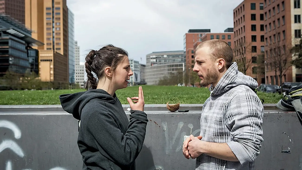 Zwei Parkour-Läufer*innen (Frau und Mann) sprechen in Gebärdensprache