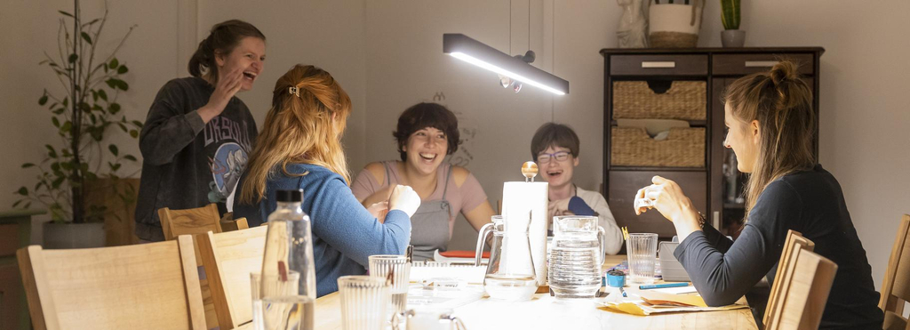 Fünf junge Frauen lachen an einem großen Tisch.
