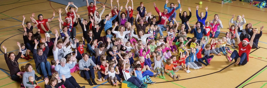 Eine große Gruppe Menschen in der Mitte einer Sporthallte. Vor ihnen liegt ein Plakat mit der Aufschrift "Bewegung Integrale Pfeffersport"