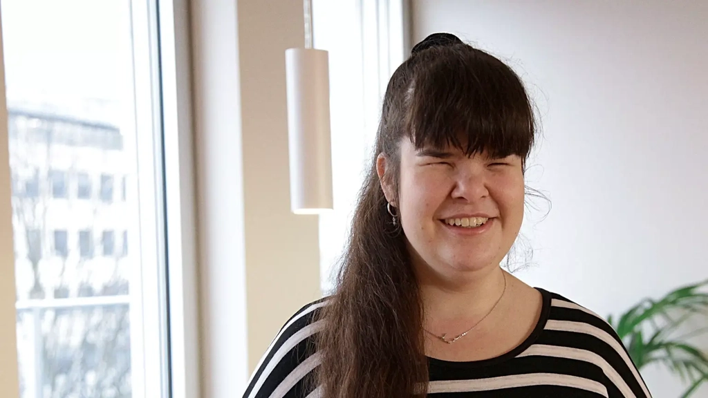 Eine junge Frau mit langem dunklem Pferdeschwanz und Ringelshirt lächelt in die Kamera.