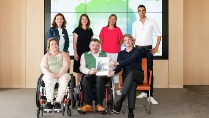 Sieben Frauen und Männer (vier stehend) drei davor in einem Konferenzraum sitzend präsentieren eine Broschüre