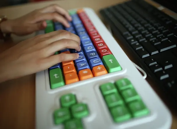 Zwei Hände auf einer bunten Tastatur.