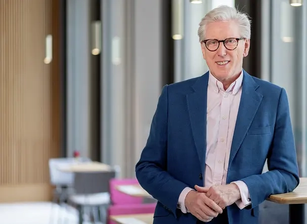 Grauhaariger Mann Mitte sechzig mit Brille in blauer Anzugsjacke