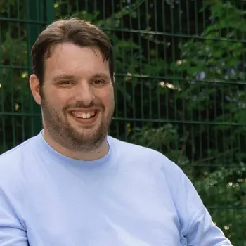 Ein junger Mann im Elektrorollstuhl auf einem Outdoor-Basketball-Platz.