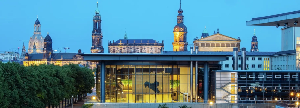 Abendlicher Blick von außen über den innen erleuchteten sächsischen Landtag hinweg auf die Wahrzeichen der Dresdener Altstatdt mit den Dächern der Frauenkirche, Semperoper und Gemäldegalerie